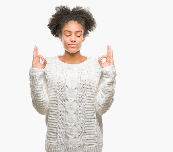 Młody afro american kobieta noszenia zimą sweter na białym tle relaks i uśmiechnięte oczy zamknięte, robi medytacji gest palcami. Joga koncepcja. - Zdjęcie, obraz