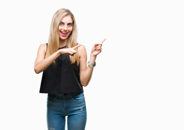 Young beautiful blonde and blue eyes woman over isolated background smiling and looking at the camera pointing with two hands and fingers to the side. - Foto, Imagen