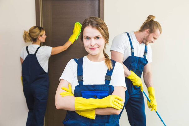 Cleaning service with professional equipment during work. professional kitchenette cleaning, sofa dry cleaning, window and floor washing. man and women in uniform, overalls and rubber gloves - Foto, Bild