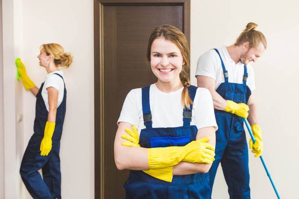 Cleaning service with professional equipment during work. professional kitchenette cleaning, sofa dry cleaning, window and floor washing. man and women in uniform, overalls and rubber gloves - Fotó, kép