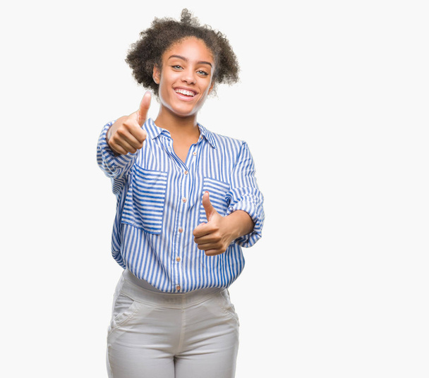 Mujer afroamericana joven sobre fondo aislado aprobando hacer gesto positivo con la mano, pulgares hacia arriba sonriendo y feliz por el éxito. Mirando a la cámara, gesto ganador
. - Foto, imagen