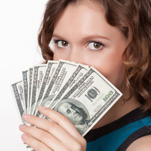 Portrait of pretty young woman holding a fan of dollar bills - 写真・画像