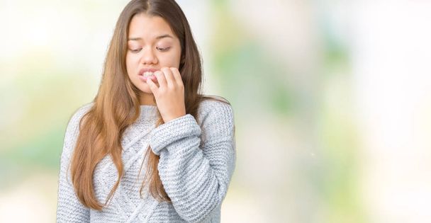 Young beautiful brunette woman wearing sweater over isolated background looking stressed and nervous with hands on mouth biting nails. Anxiety problem. - Fotoğraf, Görsel