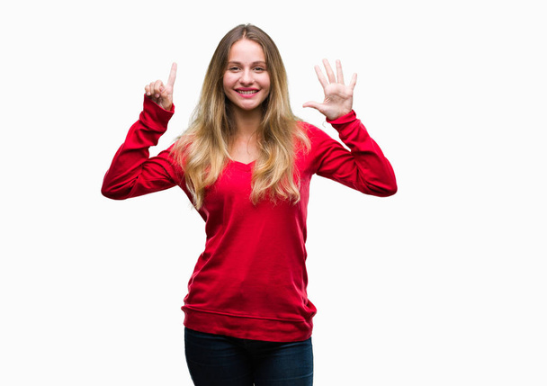 Joven hermosa mujer rubia con suéter rojo sobre fondo aislado mostrando y apuntando hacia arriba con los dedos número seis mientras sonríe confiado y feliz
. - Foto, Imagen