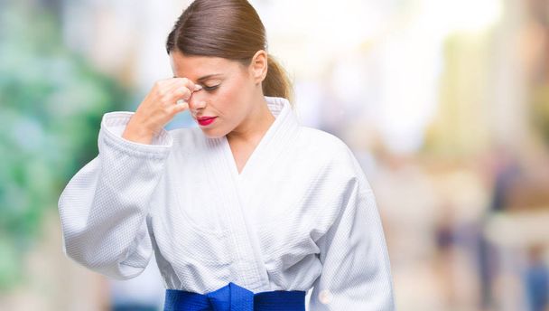 Jeune belle femme portant un uniforme de karaté kimono sur fond isolé fatigué se frottant le nez et les yeux ressentant fatigue et maux de tête. Concept de stress et de frustration
. - Photo, image