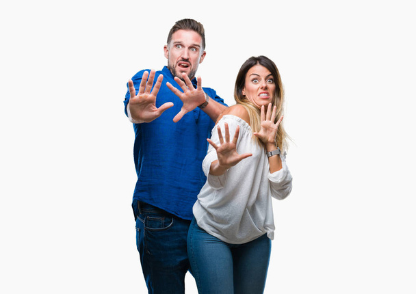 Young couple in love over isolated background afraid and terrified with fear expression stop gesture with hands, shouting in shock. Panic concept. - Photo, Image