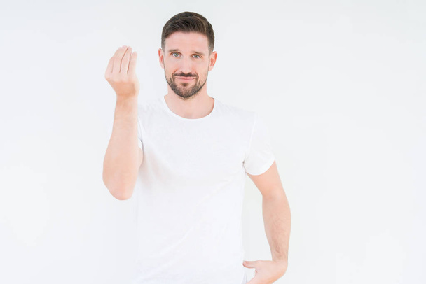 Όμορφος νεαρός φορώντας περιστασιακή λευκό t-shirt πάνω από το απομονωμένο φόντο κάνει ιταλική κίνηση με το χέρι και τα δάκτυλα ΕΝΤΟΝΗ προσωπικότητα - Φωτογραφία, εικόνα
