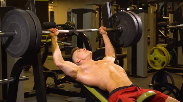 Przystojny sportowiec ćwiczenia ze sztangą na klatce piersiowej - Materiał filmowy, wideo