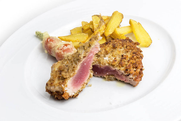 Dish of breaded red tuna fillet with tempura tomatoes and frites potatoes on white background - Photo, Image