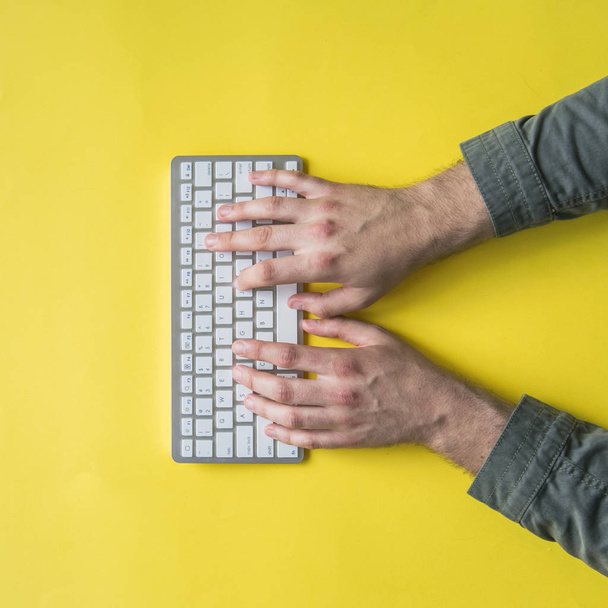 Bovenaanzicht van mans hans wiriting op een toetsenbord op een kleurrijke achtergrond, genoeg ruimte voor tekst - Foto, afbeelding