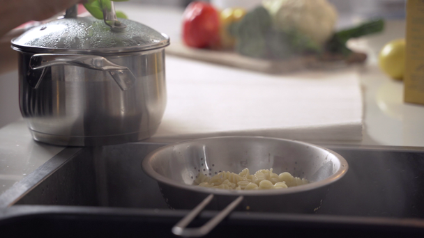 Boiling pasta. Draining macaroni water through a colander in the sink - Video