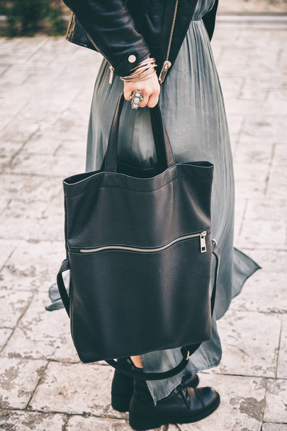 lower body detail of a stylish woman wearing jewlery, a dress and holding a big black handbag in her hands - Photo, image