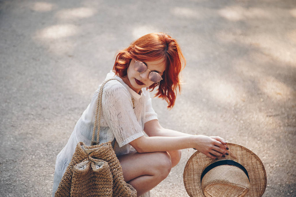 Retrato estilo calle de una hermosa mujer pelirroja con gafas de sol y posando al aire libre en un día de verano
 - Foto, Imagen