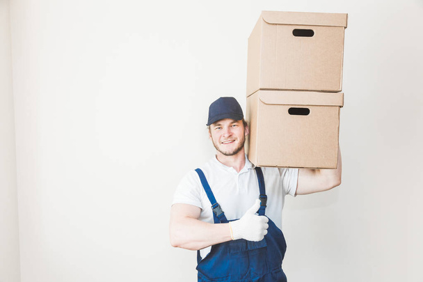 Delivery strong, muscular man loading cardboard boxes for moving to an apartment. professional worker of transportation, male loaders in overalls. free space for text, isolated - Foto, immagini