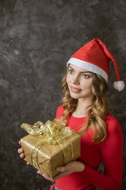 gyönyörű lány, egy karácsonyi ajándék öltözött egy karácsonyi kalap - Fotó, kép