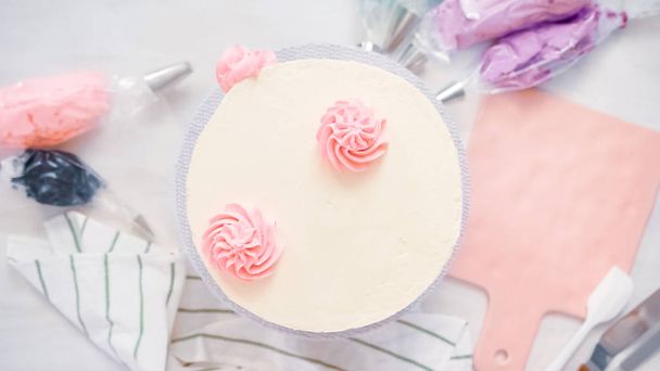 Pose plate. Tuyauterie rosettes crème beurre couleur pastel sur un gâteau blanc pour faire un gâteau de licorne
. - Photo, image