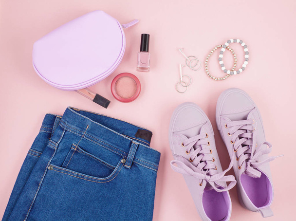Blog de mode ou concept de magazine. Baskets féminines roses, jeans et maquillage sur fond rose pastel. Pose plate, vue du dessus fond minimal
. - Photo, image