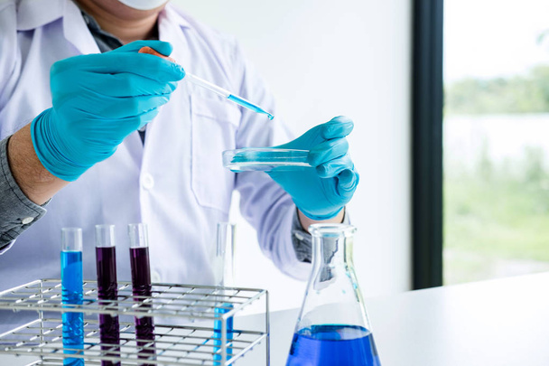 Biochemistry laboratory research, Chemist is analyzing sample in laboratory with equipment and science experiments glassware containing chemical liquid. - Photo, Image