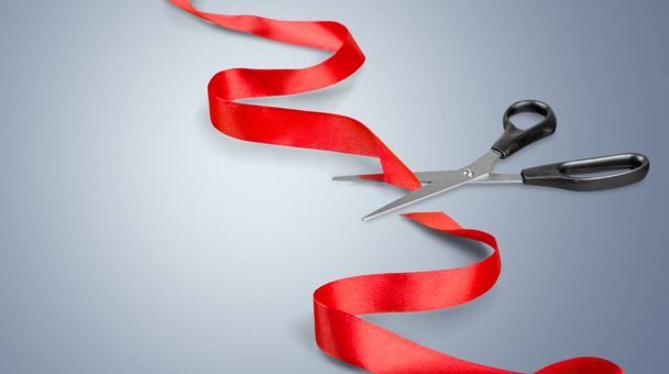 Scissors cutting red ribbon, close-up view on background - 写真・画像