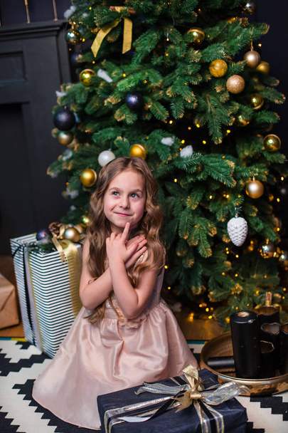 Little girl under the Christmas tree. A girl with gifts under the tree in anticipation of magic, a gift from Santa Claus - Valokuva, kuva