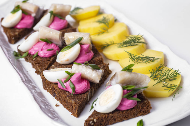 Traditional Russian Food: Potatoes and herring with black bread on white plate. - Fotografie, Obrázek