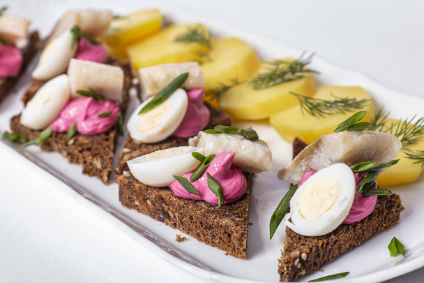 Traditional Russian Food: Potatoes and herring with black bread on white plate. - Fotografie, Obrázek