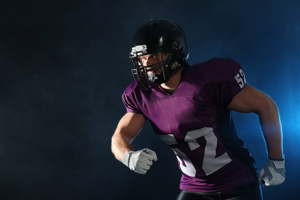 American football player wearing uniform on dark background. Space for text - 写真・画像