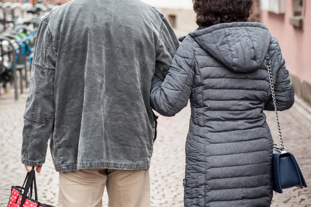 closeup of couple back entwined walking in the street by winter - Foto, immagini