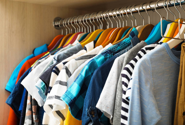 Hangers with teenage clothes on rack in wardrobe, closeup - Фото, изображение