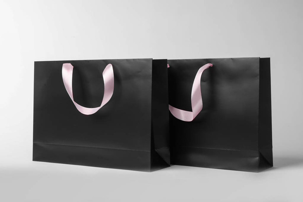 Paper shopping bags with ribbon handles on white background. Mockup for design - Foto, Bild
