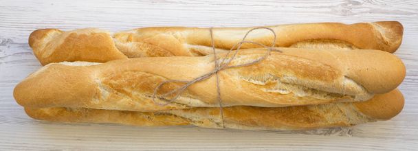 Fresh french baguettes on white wooden surface, toverhead view. Close up. - Photo, Image