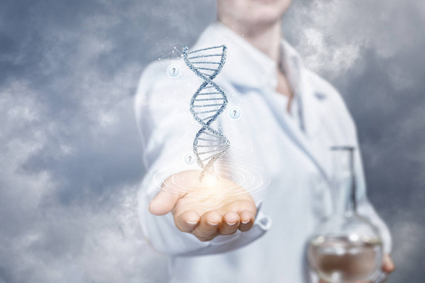 Un asistente de laboratorio está mostrando un modelo de ADN en una mano y sosteniendo un frasco con sustancia transparente en otra. El concepto es las innovaciones en las investigaciones del ADN
. - Foto, Imagen