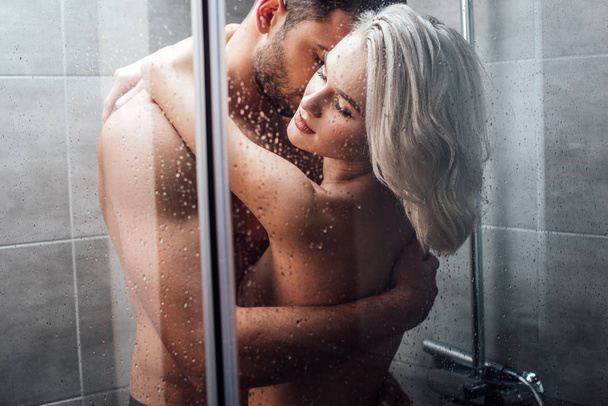 beautiful naked heterosexual couple hugging and taking shower together - Photo, image