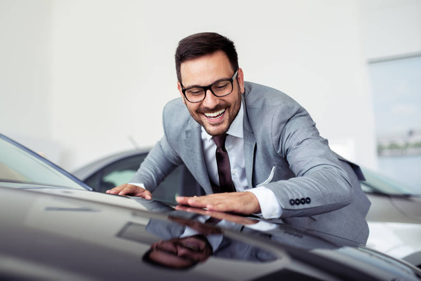 Young man is choosing a new vehicle in car dealership  - Foto, Imagen