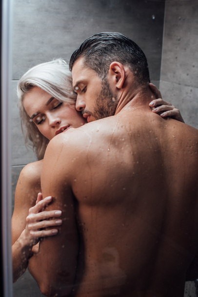 young passionate couple hugging and kissing while taking shower together - Photo, Image