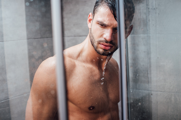 handsome naked muscular man taking shower in bathroom - 写真・画像