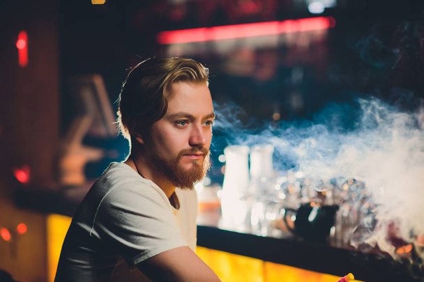 Young Man Smoking Shisha At Arabic Restaurant - Man Exhaling Smoke Inhaling From A Hookah. - Фото, изображение