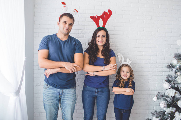 Christmas family photo. Father, mother and daughter are wearing christmas funny horns. - Foto, Imagem