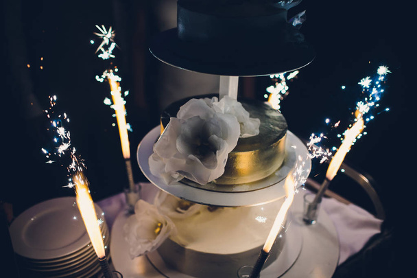 The wedding cake with fireworks stand on the table in restaurant. - Фото, изображение
