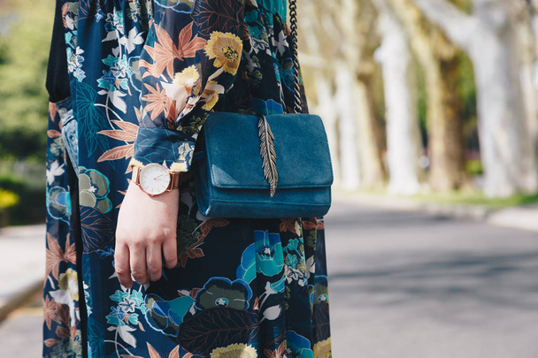 detalhes de moda estilo de rua. close up, jovem blogueiro de moda vestindo uma jaqueta floral, e um relógio de pulso analógico branco e dourado. verificando o tempo, segurando uma bela bolsa de couro de camurça
. - Foto, Imagem