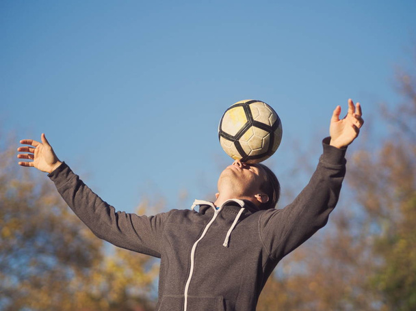 Футболист балансирующий футбол в парке в солнечный осенний день
 - Фото, изображение