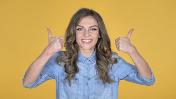 Νεαρό κορίτσι χειρονομώ Thumbs Up απομονώνονται σε κίτρινο φόντο - Πλάνα, βίντεο