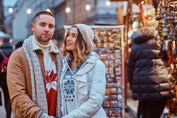 Szczęśliwa para romantyczny trzymając się za ręce, stojąc na ulicy w czasie świąt Bożego Narodzenia, ciesząc się, spędzać czas razem. - Zdjęcie, obraz