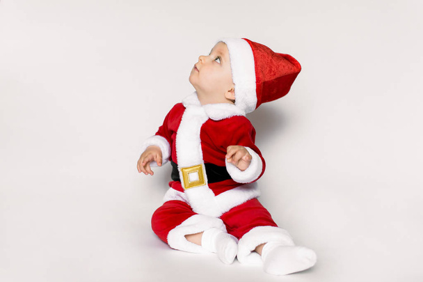 Beautiful little baby celebrates Christmas. New Year's holidays. Baby in a Christmas costume with gift - Foto, Imagen