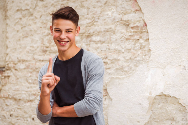 Portrait of the smiling young man who is standing outdoor near the old house wall - Foto, immagini