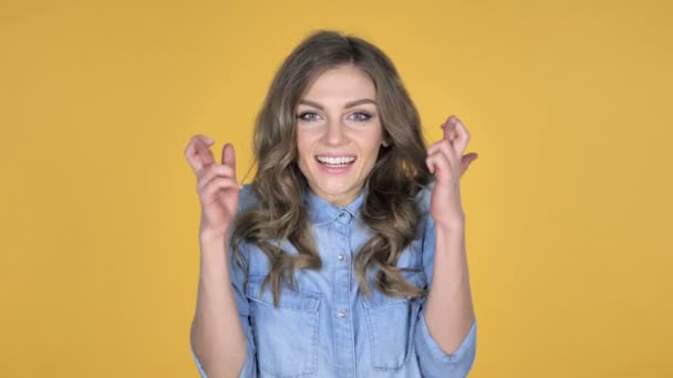 Bezorgd meisje, permanent met vinger gekruist voor goed geluk op gele achtergrond - Video
