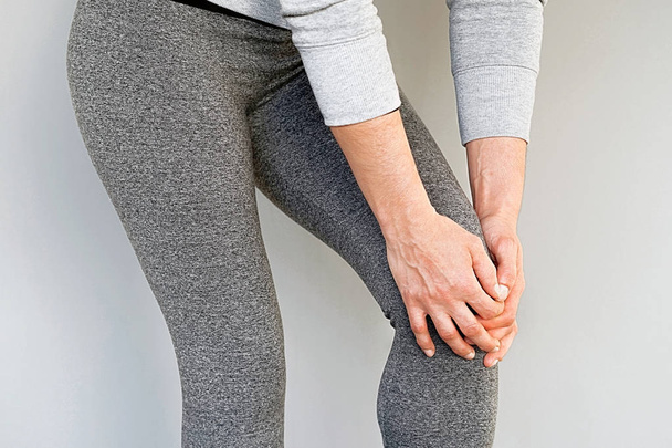 Pain In Knee. Close-up Female Leg With Painful Knees. Woman Feeling Joint Pain, Having Health Issues And Touching Leg With Hands. Body And Health Care Concept. - Foto, imagen