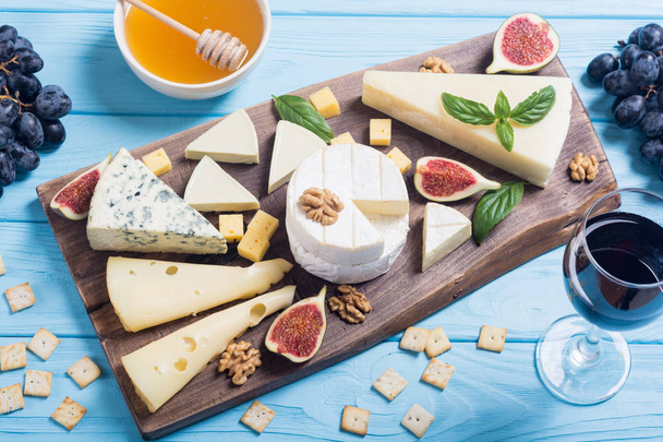 Cheeseboard with cheese brie , parmesan , camembert and dorblu . Food on wooden board - Fotó, kép