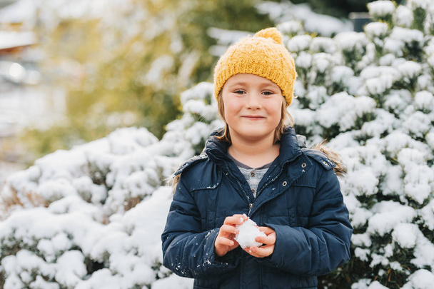 Joyeux petit garçon jouet avec neige à l'extérieur, veste d'hiver chaude et chapeau jaune
 - Photo, image