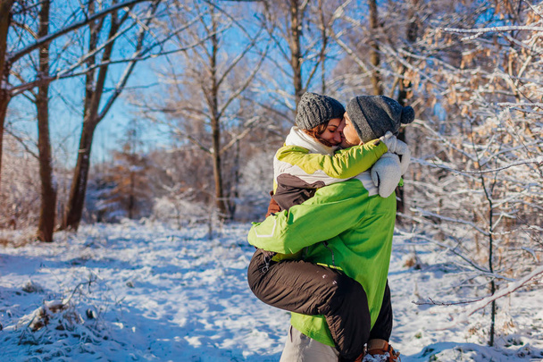 Gelukkige paar verliefd wandelen en knuffelen in winter woud. Man bedrijf vriendin. Jonge mensen plezier - Foto, afbeelding
